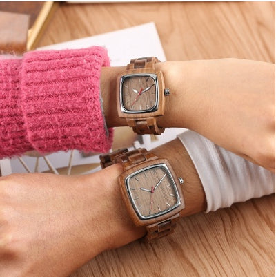 Couple wearing matching wooden watches with square faces and wooden link bands.