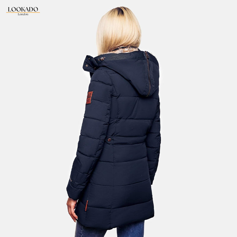 Rear view of a woman wearing a navy blue puffer coat with a faux fur-lined hood. The coat falls to the mid-thigh and has a small leather patch on the upper back.