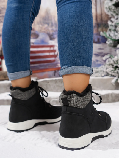 Woman wearing a black winter boots with warm lining and white soles, perfect for snowy conditions.