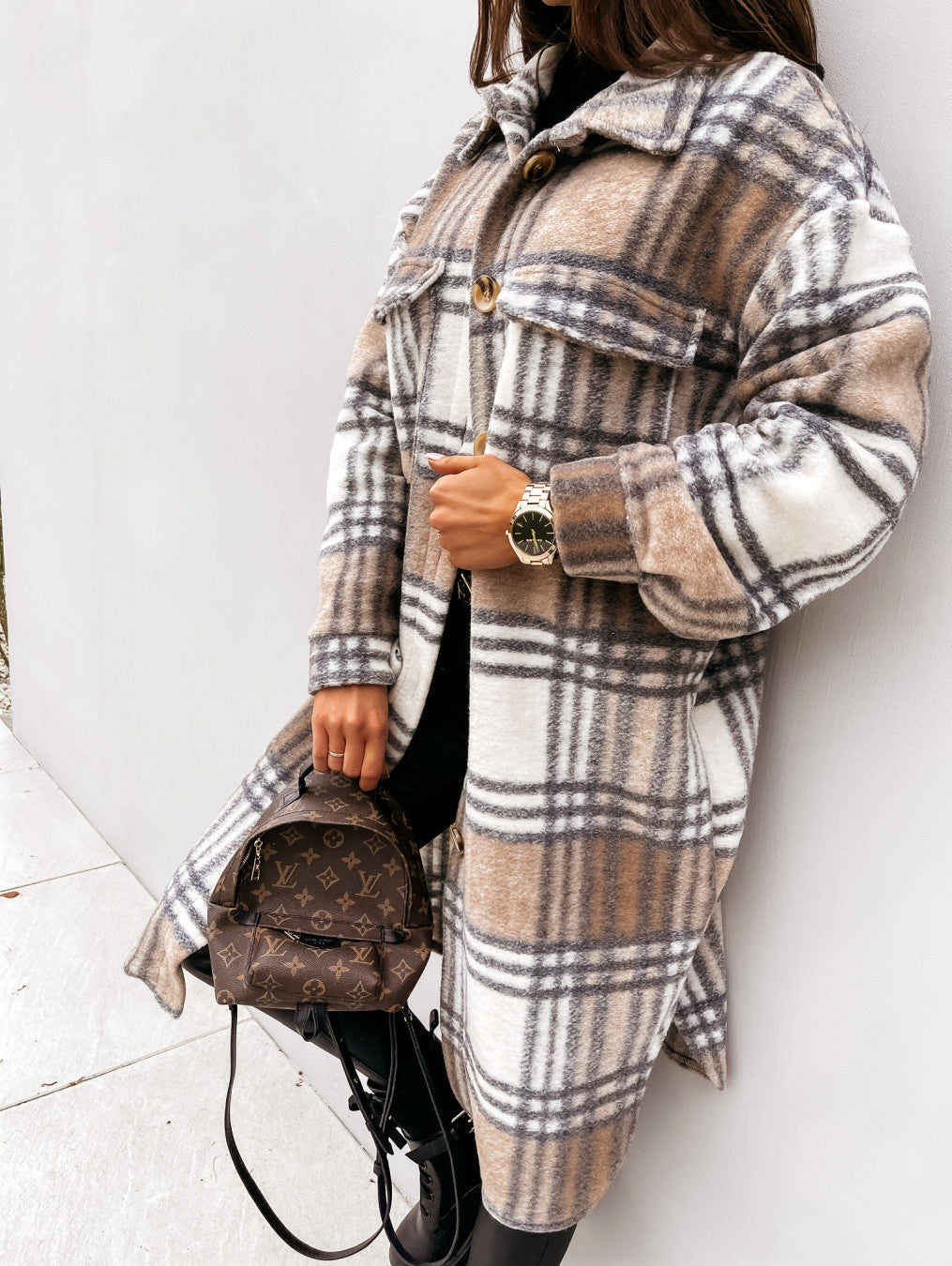 Woman wearing a brown and white plaid coat with a button front and two chest pockets.