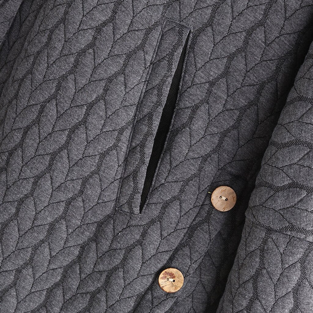 Close-up of the pocket and button detail on a grey quilted coat.