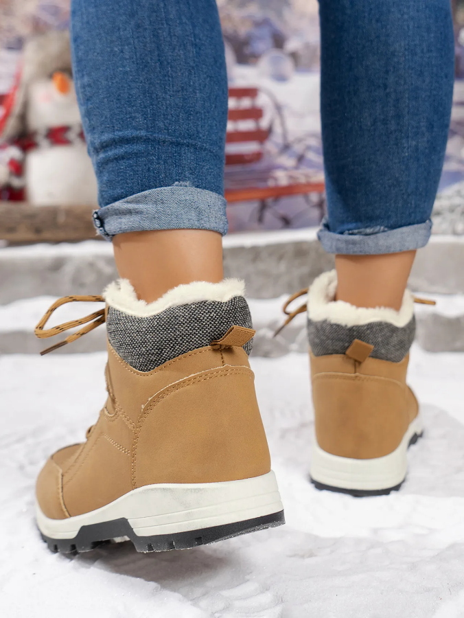 Rear view of woman wearing tan winter boots with warm lining, walking in the snow.