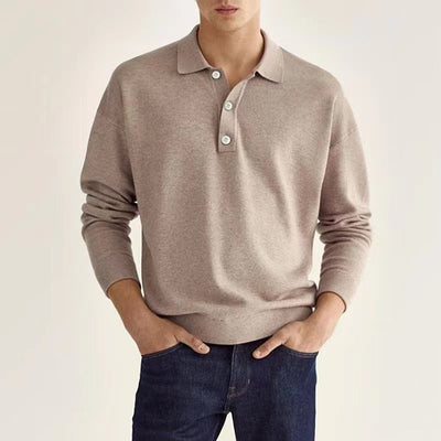 A man wearing a beige polo sweater paired with casual denim.