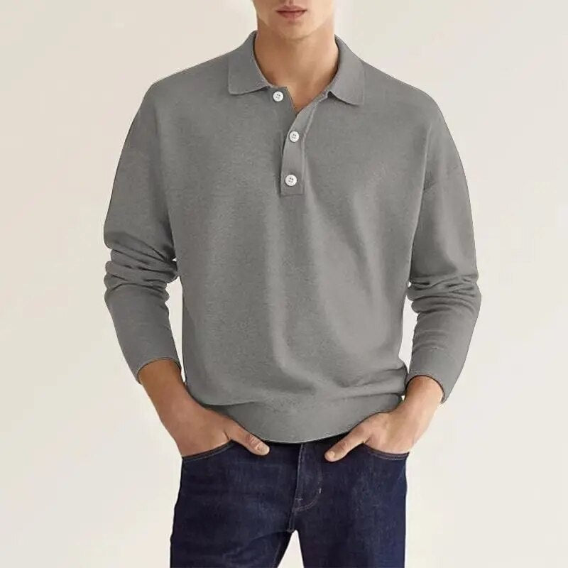 A man in a classic gray polo sweater styled with denim pants.