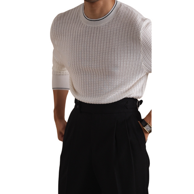 Men's white knit sweater paired with black pleated trousers.