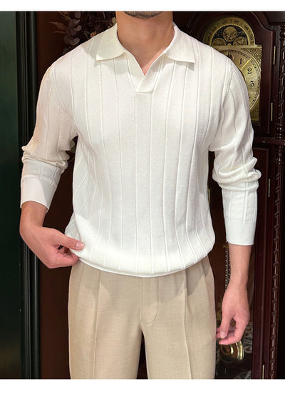 A men's white knit sweater with a collared neckline and ribbed pattern, captured from the side, styled with beige trousers.