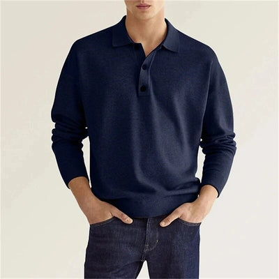 A man wearing a navy blue polo sweater styled with denim pants.