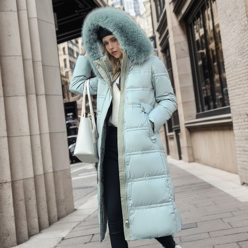 A woman dressed in a green down jacket and black pants poses outdoors, showcasing her stylish winter outfit.