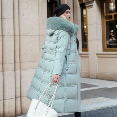 A woman in a stylish blue down coat featuring a fur collar, enjoying a cold day outside.